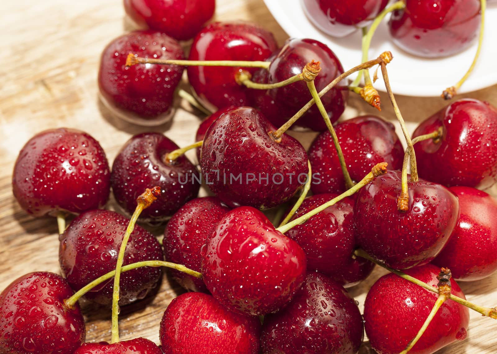 Photographed close-up ripe red cherries covered with drops of water, little depth of field, berries are on the wooden table