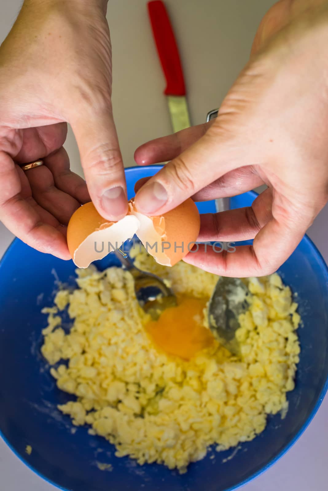 hand pours out raw egg of the shell in shortbread dough