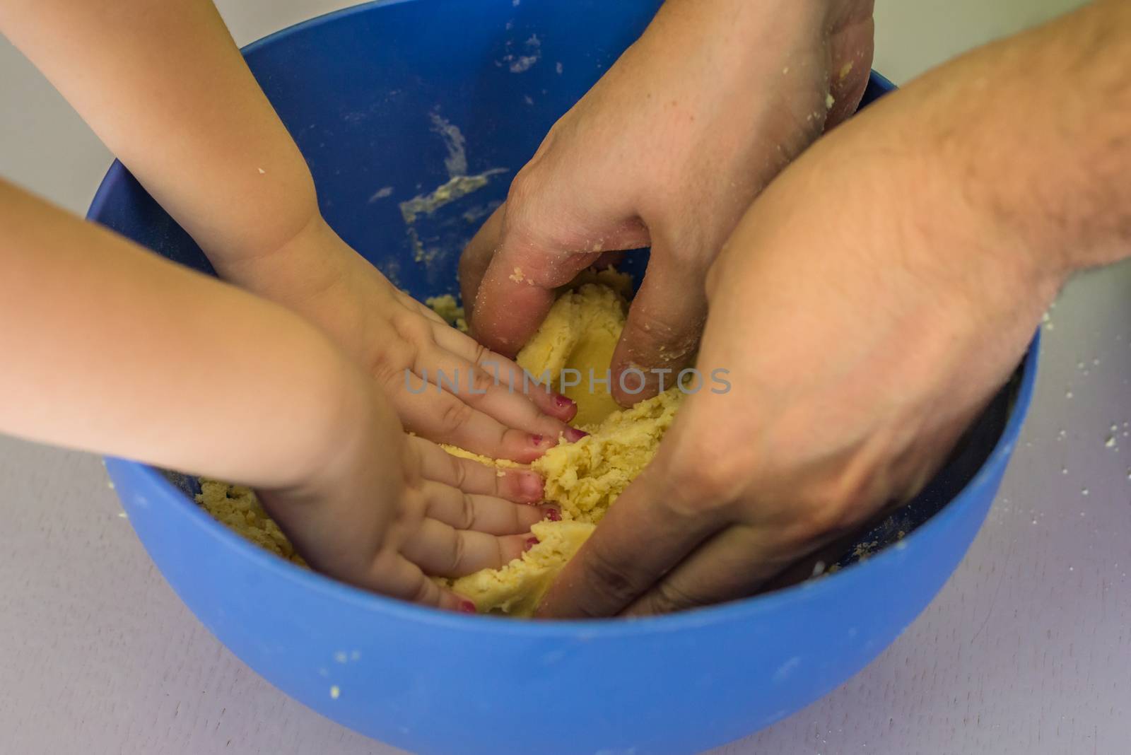 Children and dad hands preparing shortbread dough in blue bowl