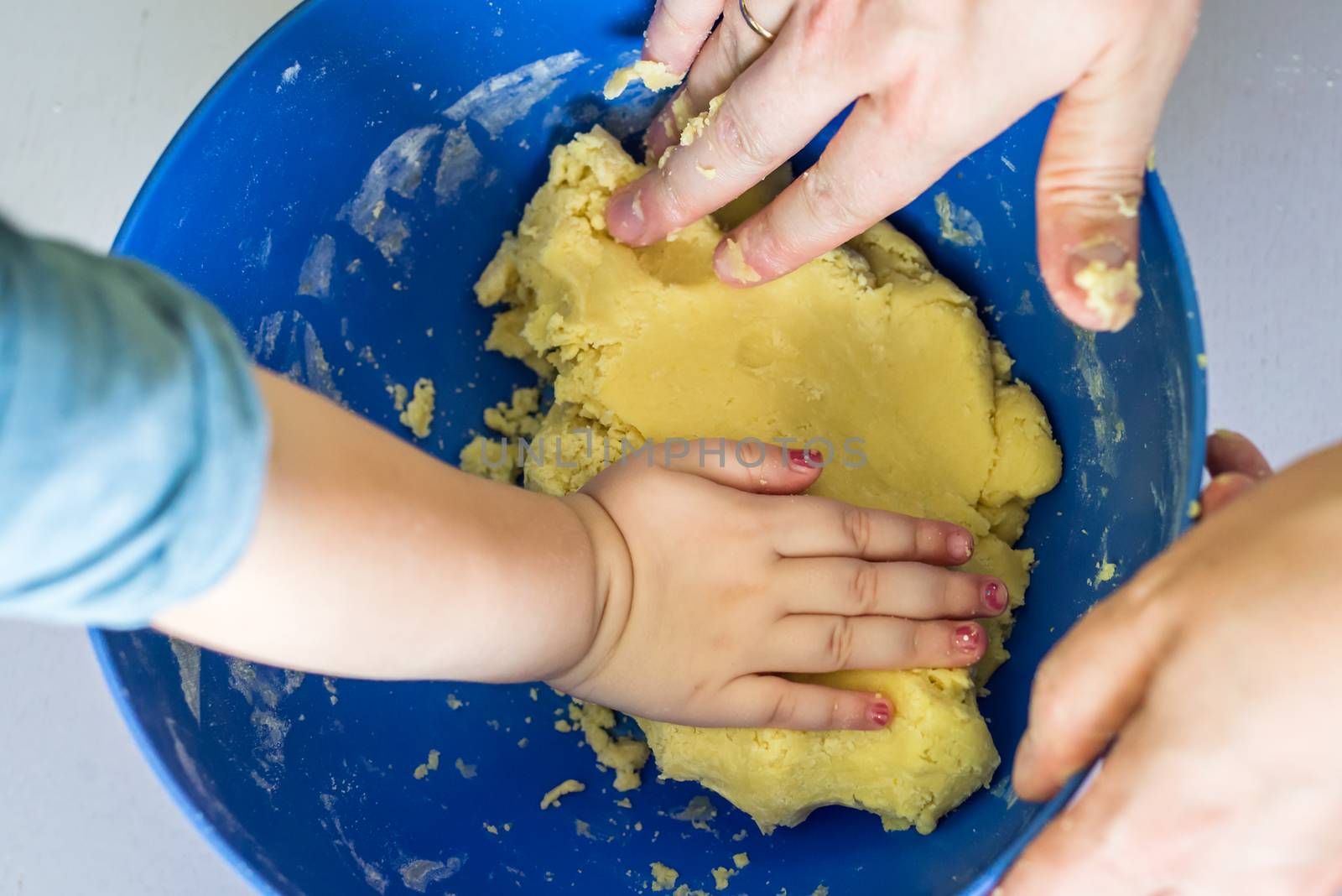 Children and dad hands preparing shortbread dough in blue bowl