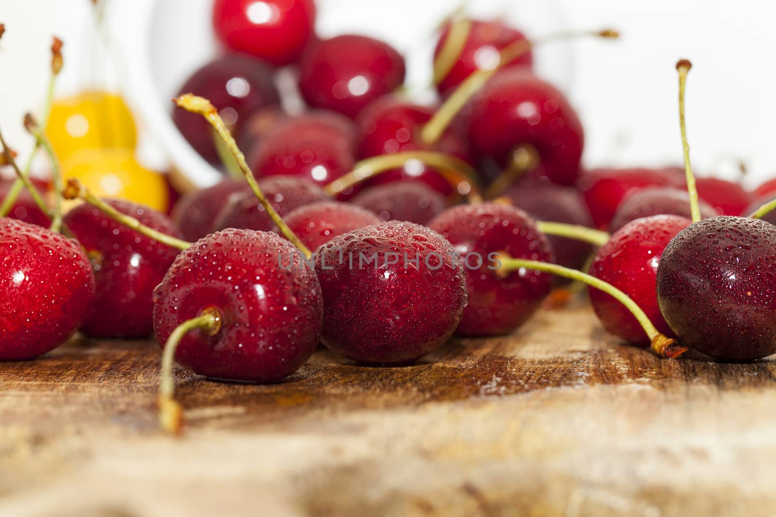 Photographed close-up ripe red cherries covered with drops of water, little depth of field, berries are on the wooden table