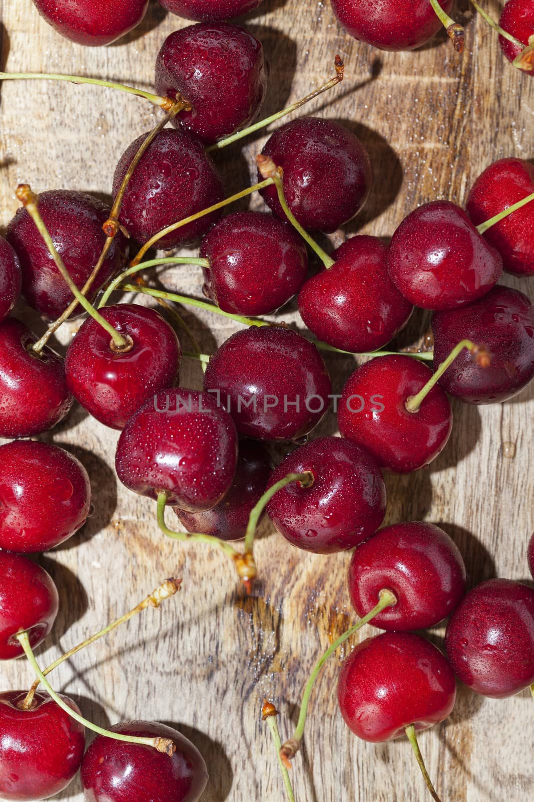 Photographed close-up ripe red cherries covered with drops of water, little depth of field, berries are on the wooden table