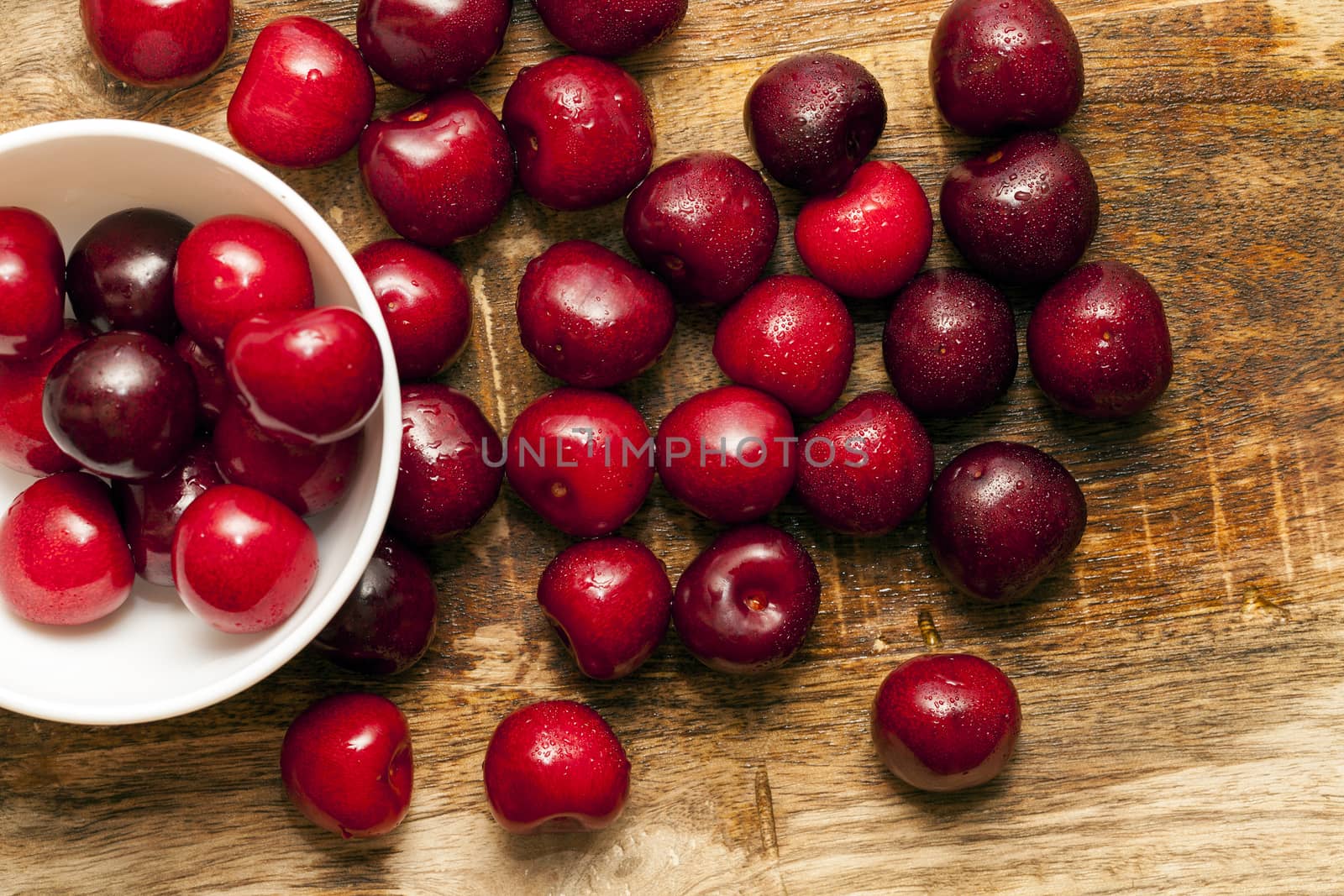 photographed close-up of ripe red cherries covered with water drops, shallow depth of field, photo taken from above. Berries on the table