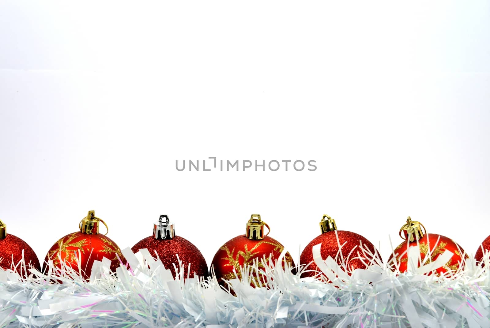 Several red and silver colored Christmas balls Placed in front of a white garland