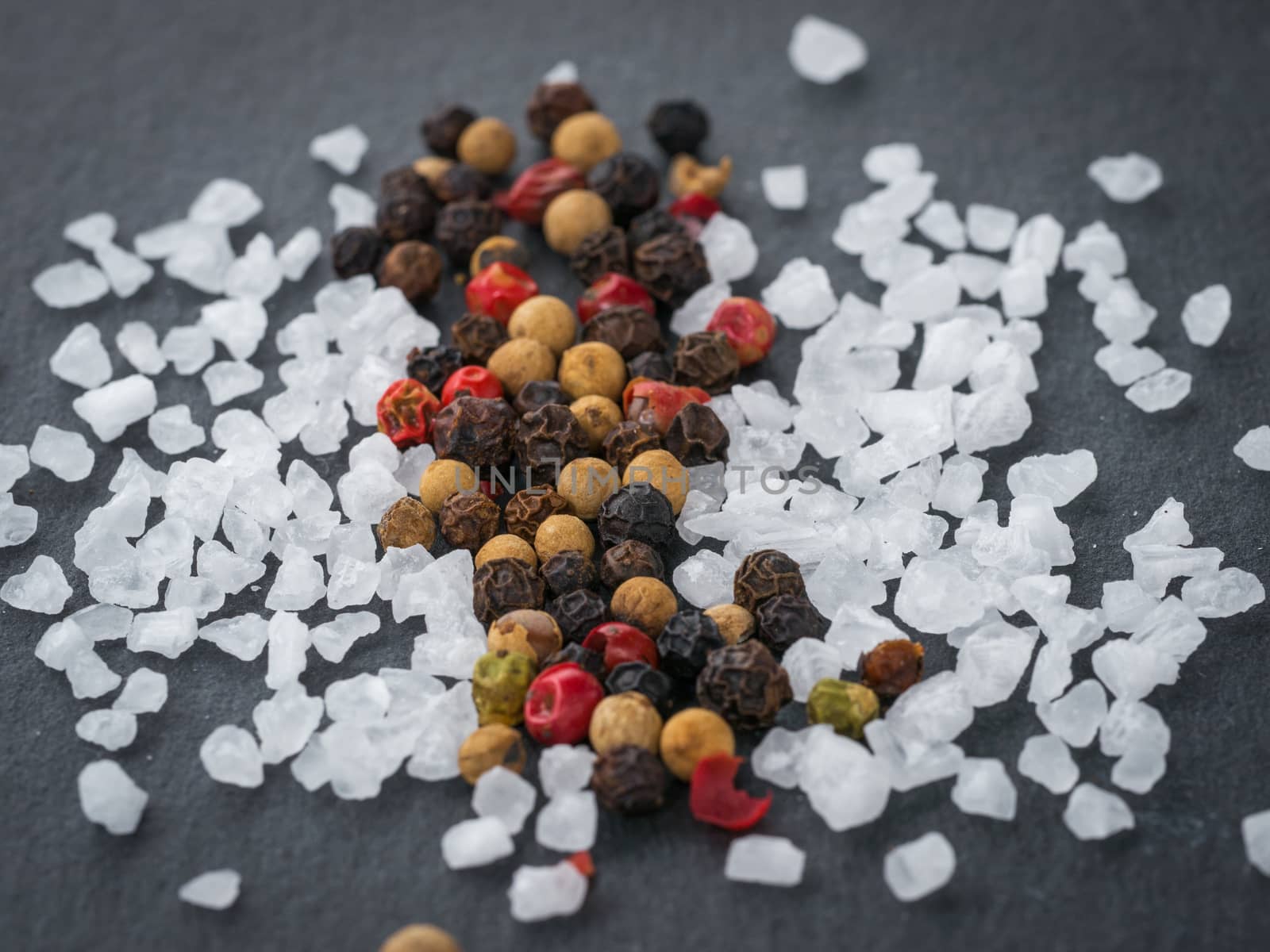 Coarse sea salt and peppercorns on slate background.Close up. Food background