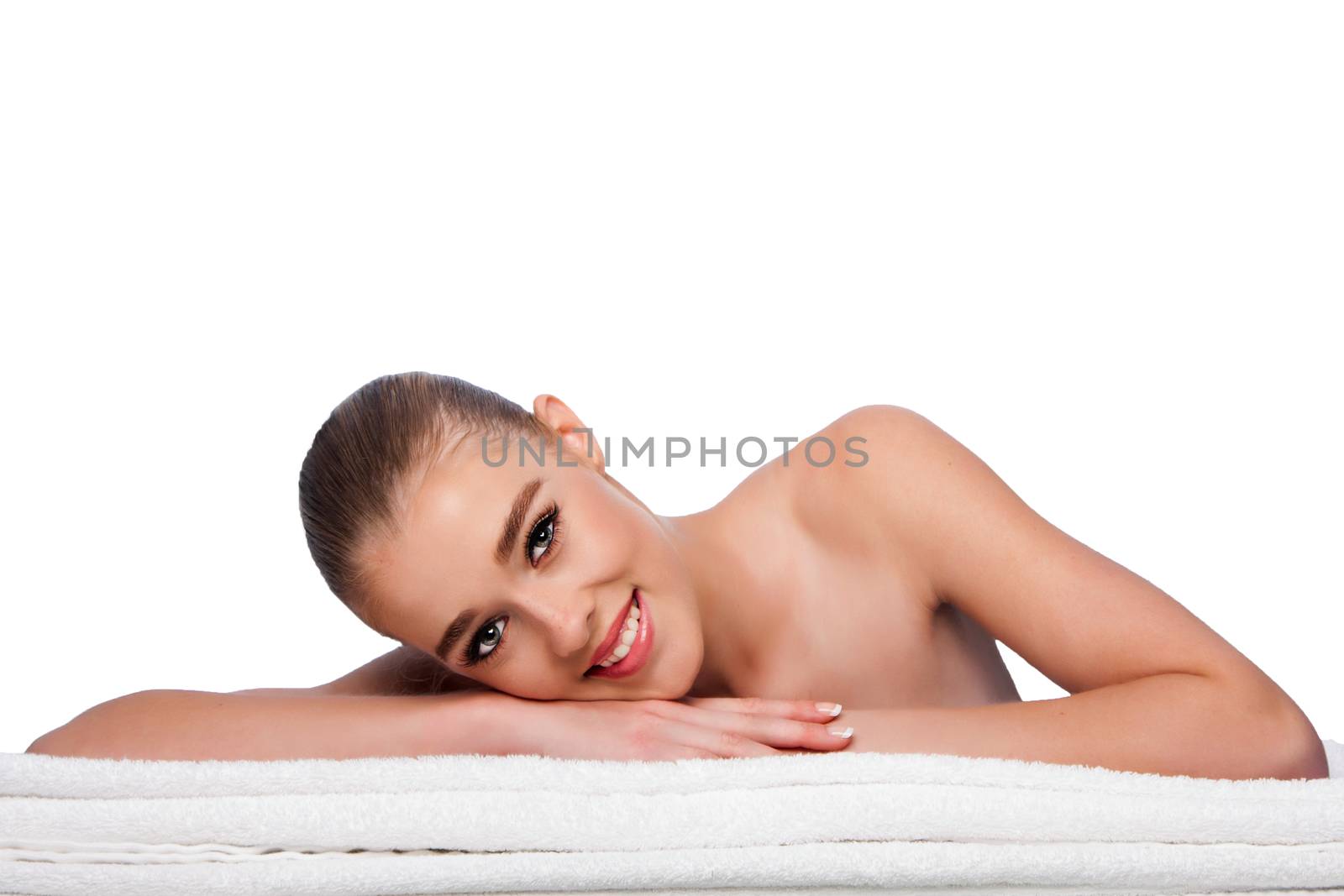 Beautiful woman at spa laying on towels waiting for exfoliating skincare treatment, on white.