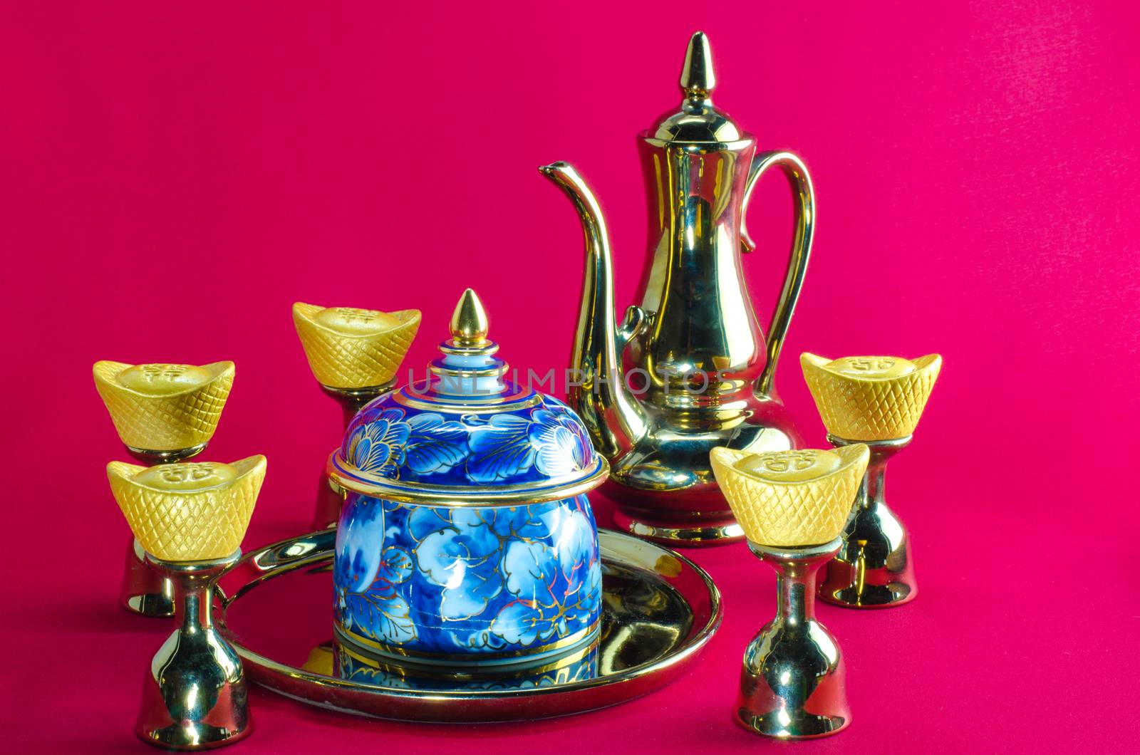 Gold ingot Gold jug Tea glass benjarong  on red background.