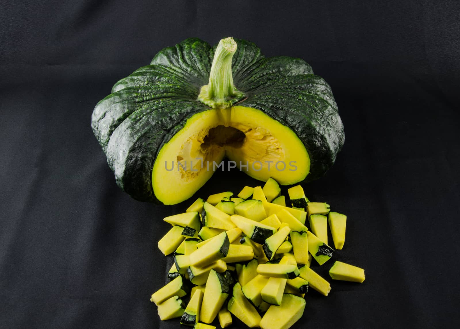 Sliced raw yellow pumpkin on black background. Sliced yellow pumpkin and green pumpkin for use as cooking ingredients