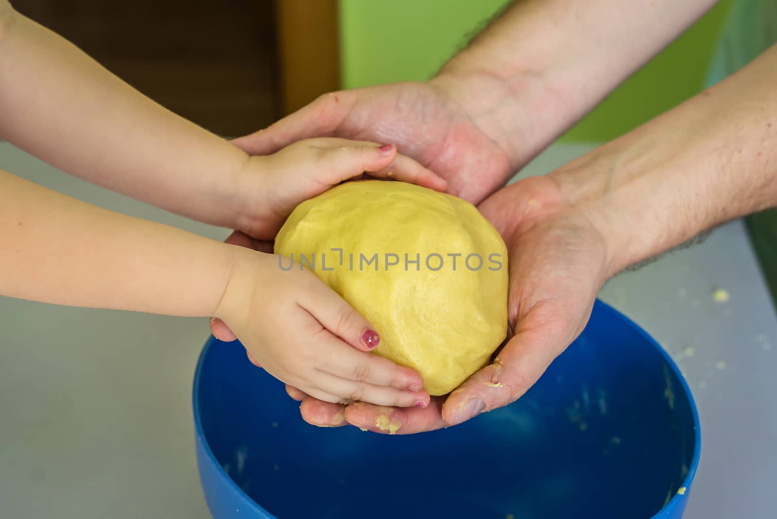 Children and dad hands hold the shortcrust dough over the table