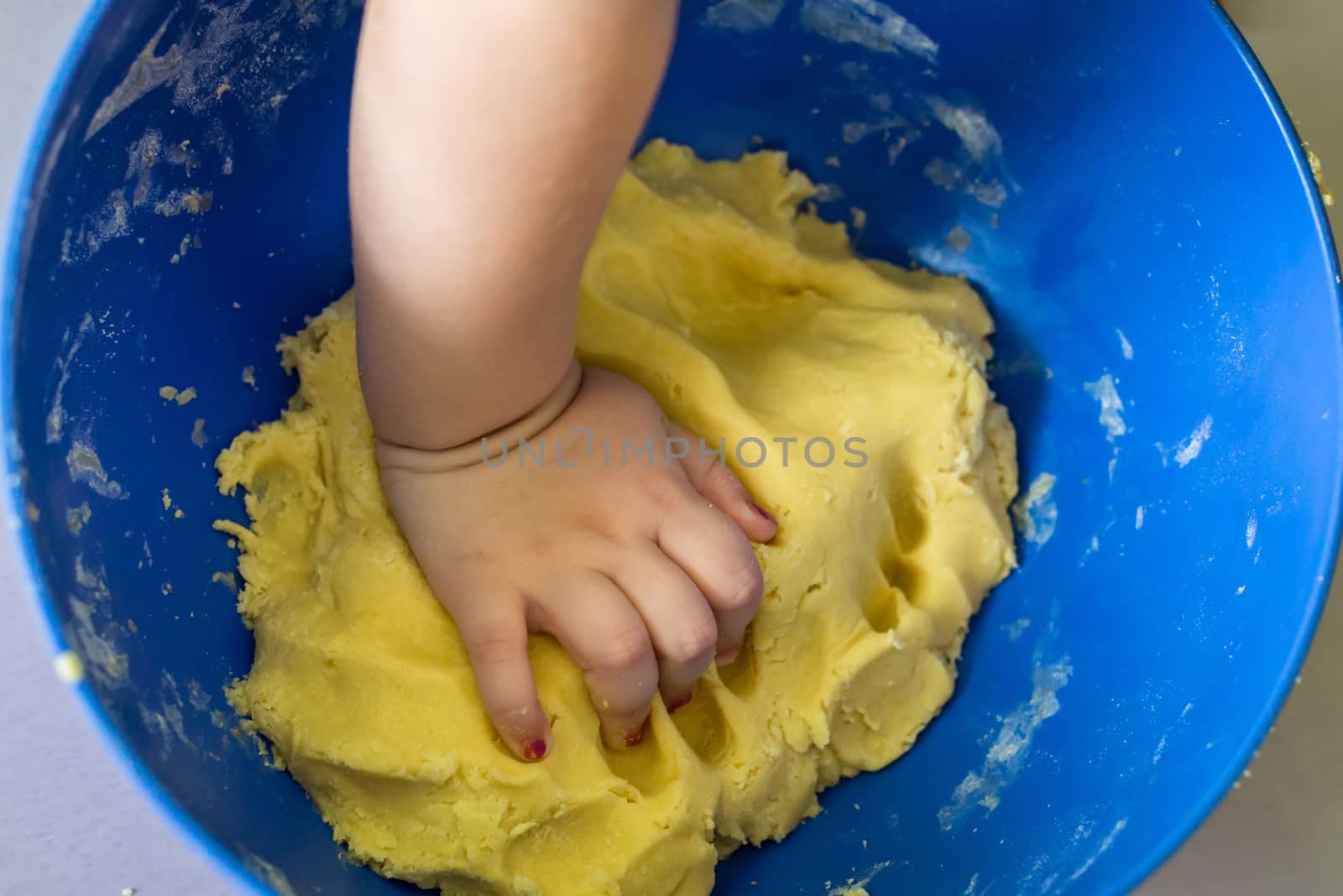 little hand prepares the shortcrust pastry in blue bowl