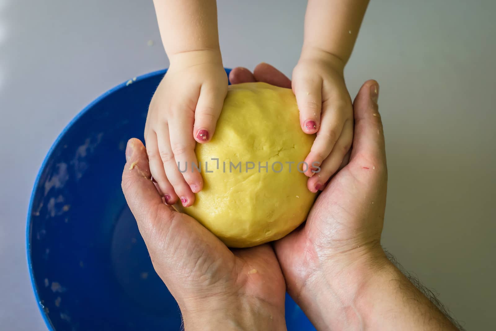 Children and dad hands hold the shortcrust dough over the table