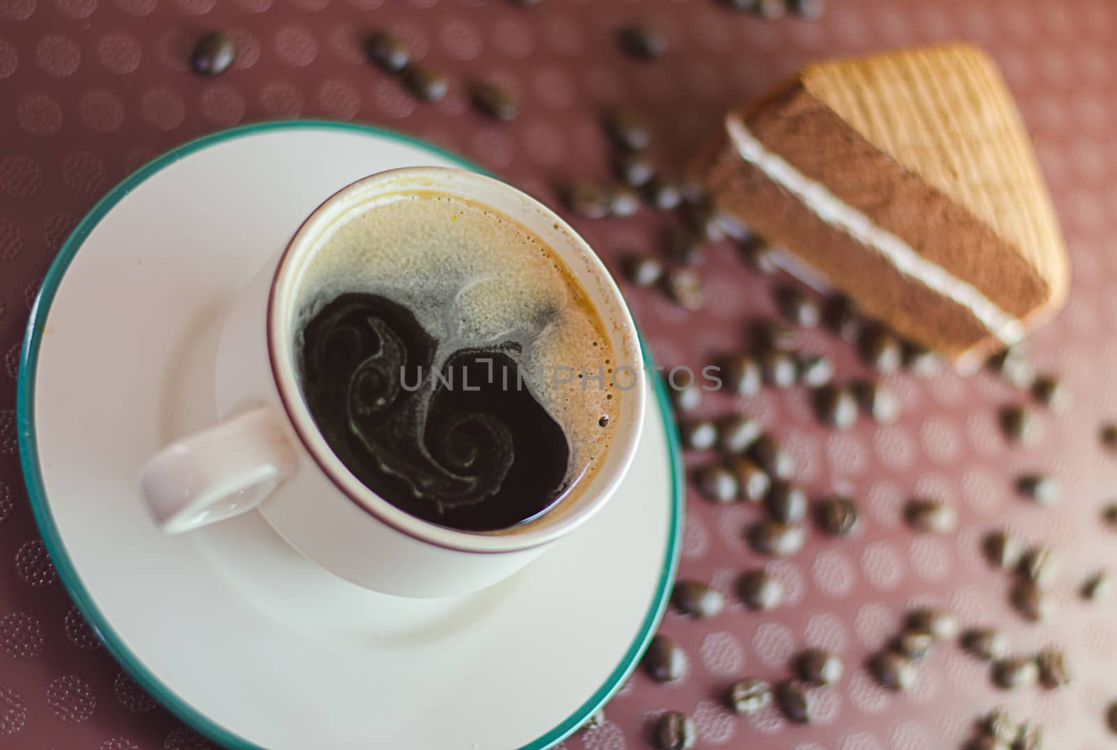 A cup of coffee with slice of chocolate cake on tray background