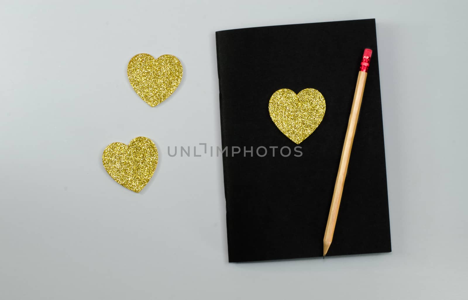 Heart of gold with a black pencil on a plate. by metal22