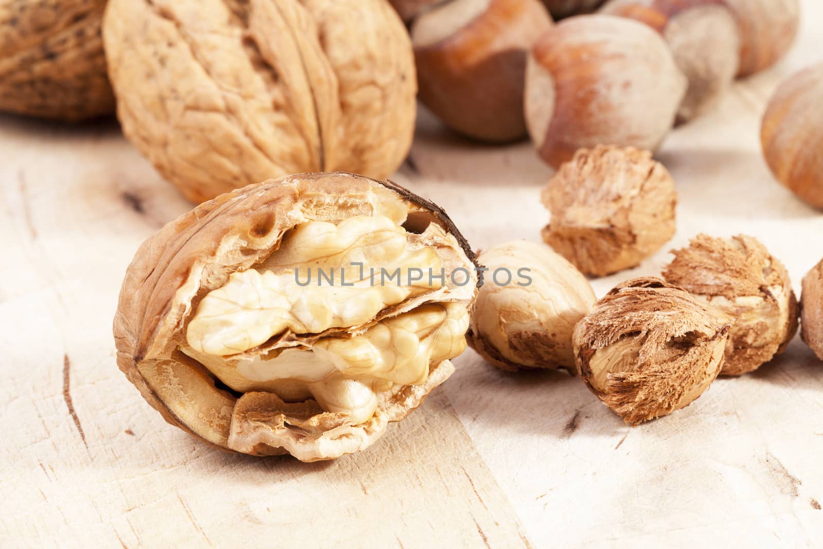 Composition of hazelnuts and walnuts on wooden plank, close up