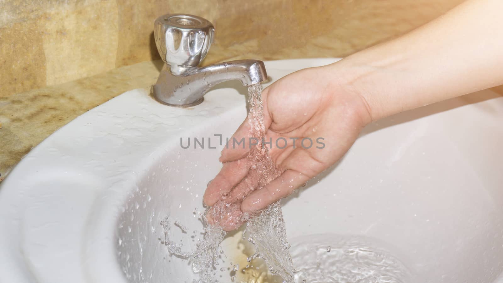 Boy washes hands with running water by nopparats