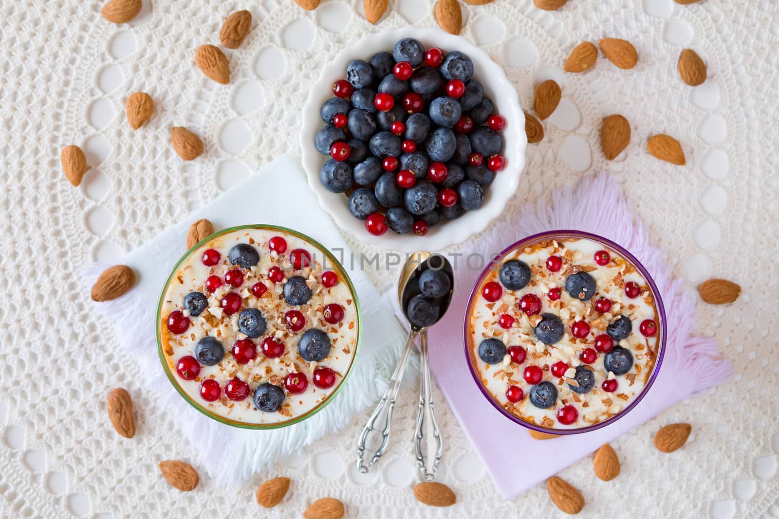 Two yogurt dessert with berries and almonds seen from above with almonds around