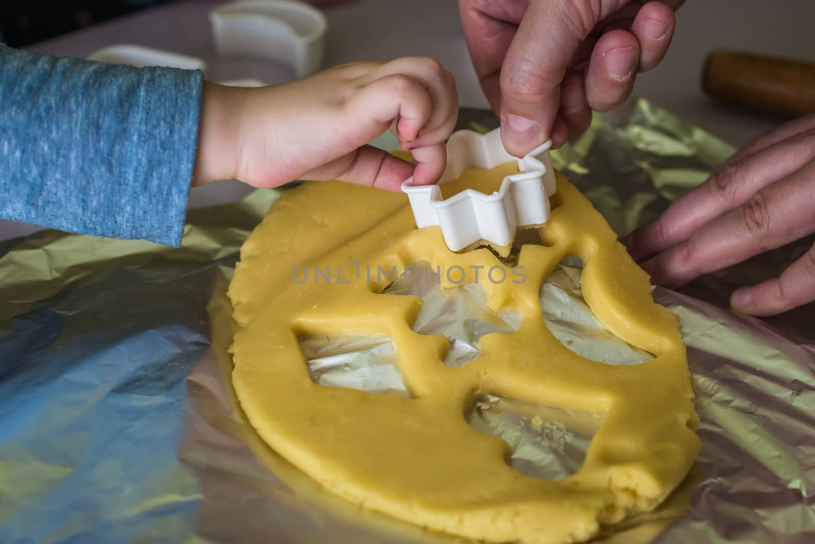 child and dad makes shape of shortcrust dough with cookie cutters