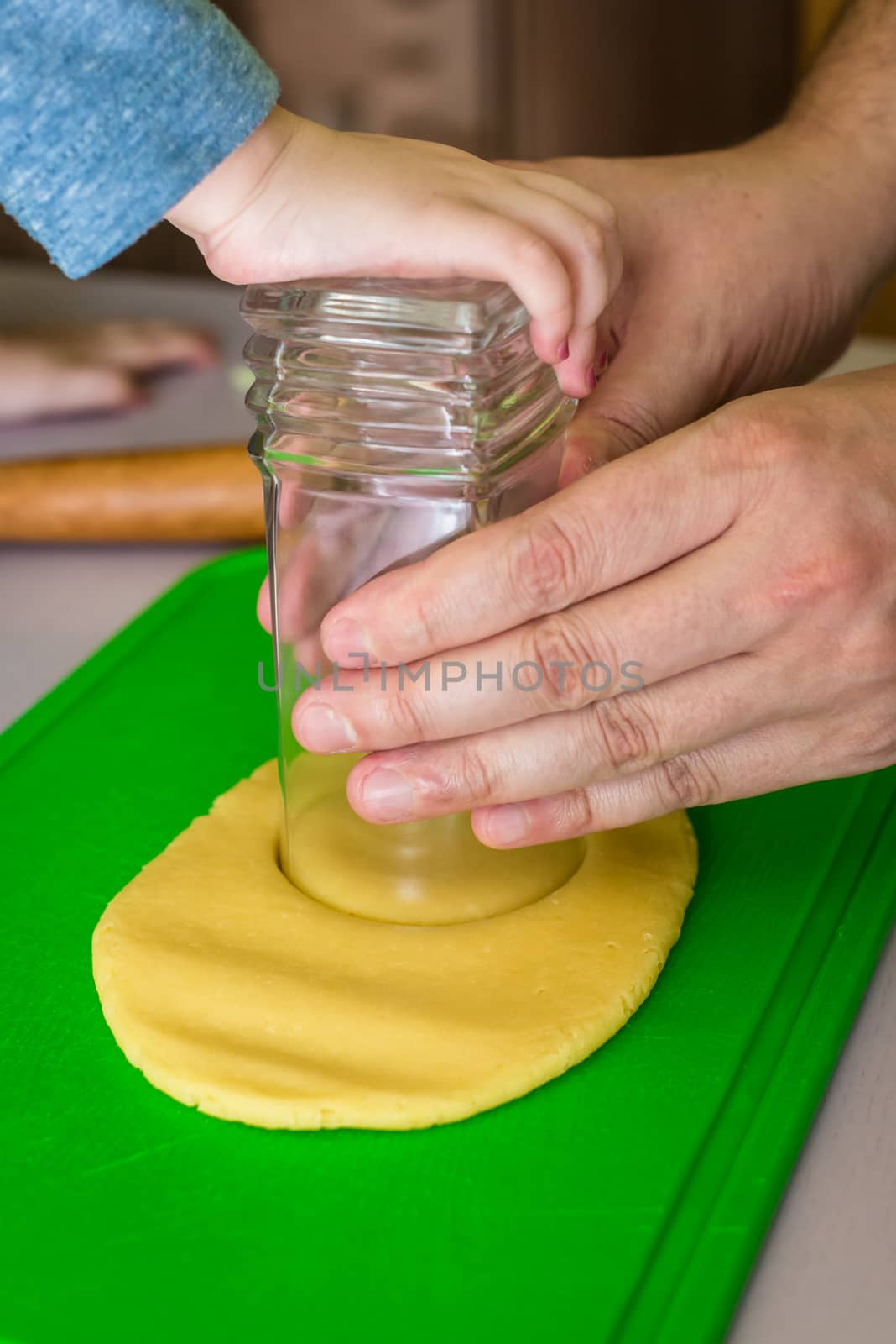 Children and dad hands cook the circles of shortcrust dough