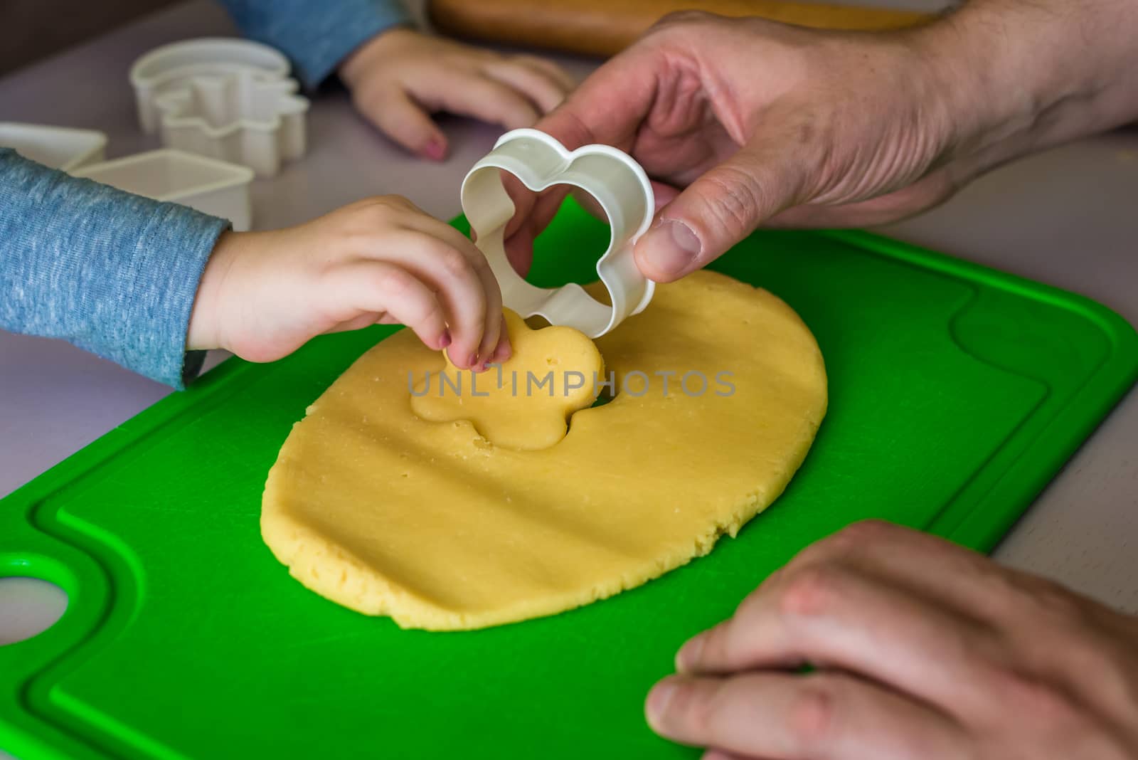 child and dad makes shape of shortcrust dough with cookie cutters