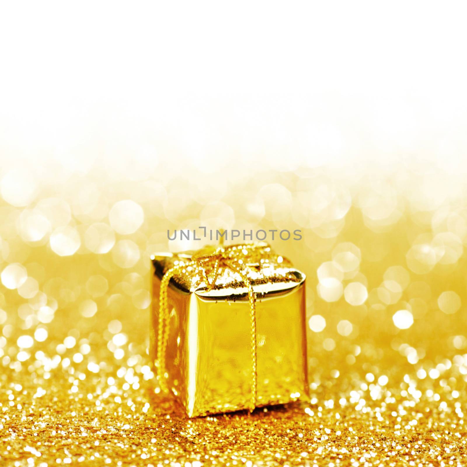 Decorative golden box with holiday gift on shiny glitter background