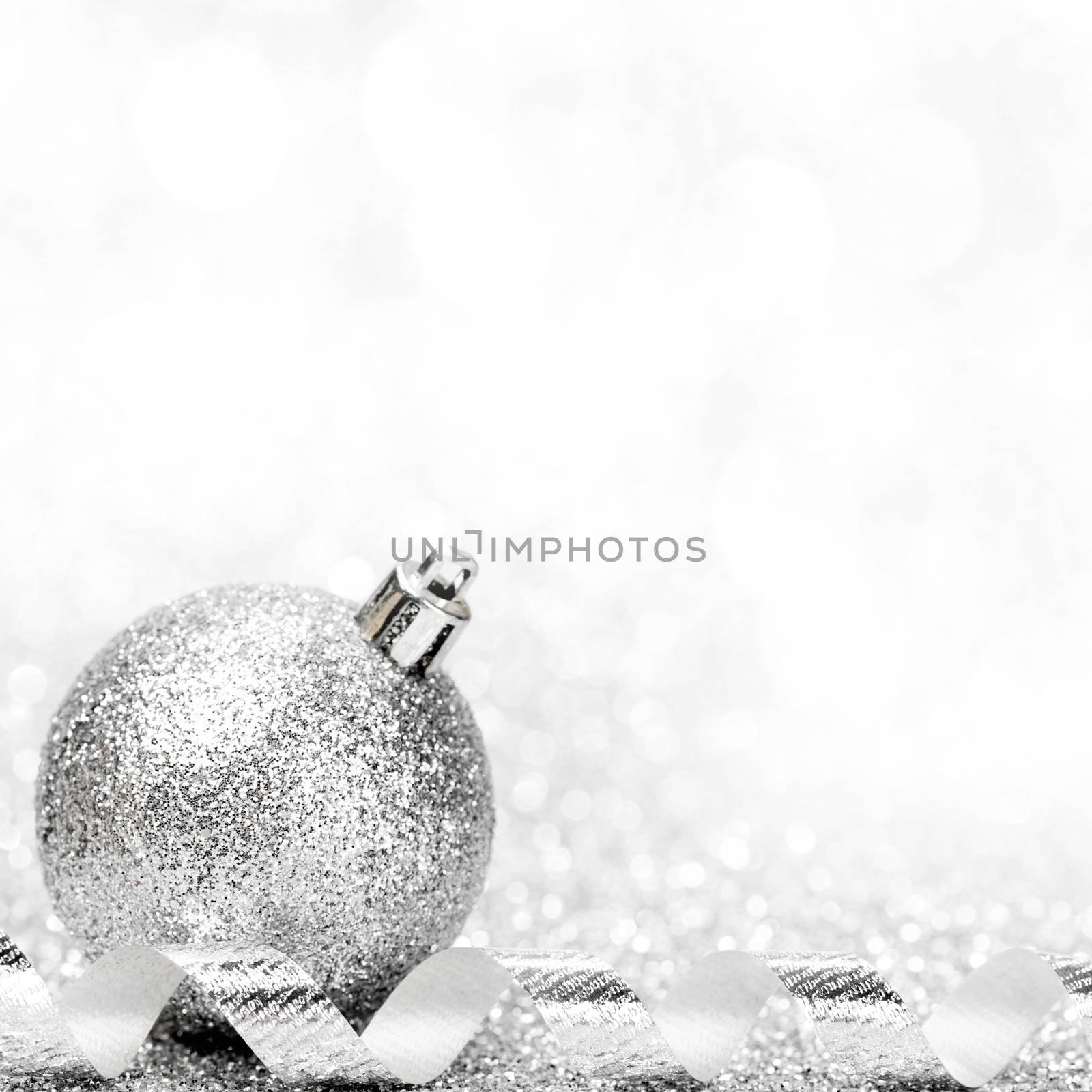 Christmas ball and curly decorative ribbon on bokeh background