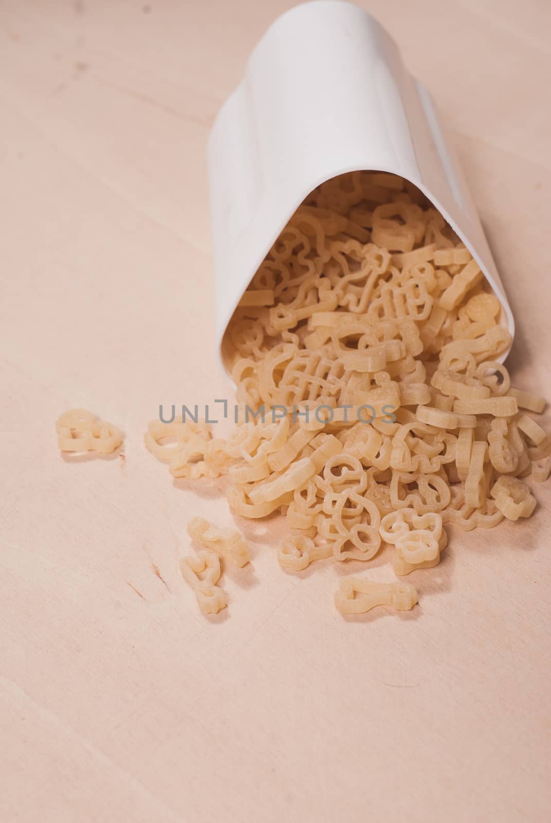 The pasta scattered across the wooden surface, white container, healthy food concept