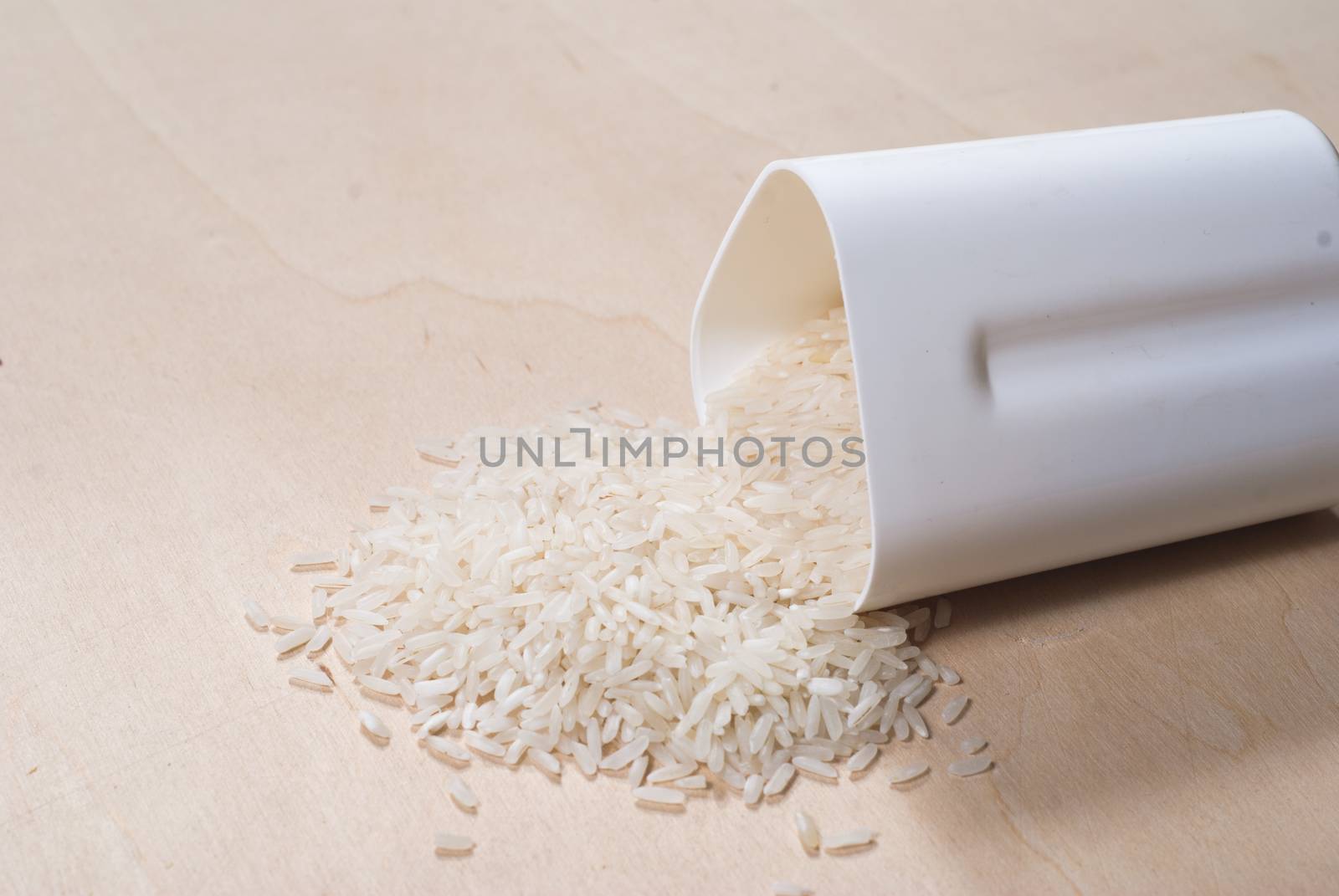 Rice scattered on the wooden surface, rice cereal in the white container, the concept of healthy eating