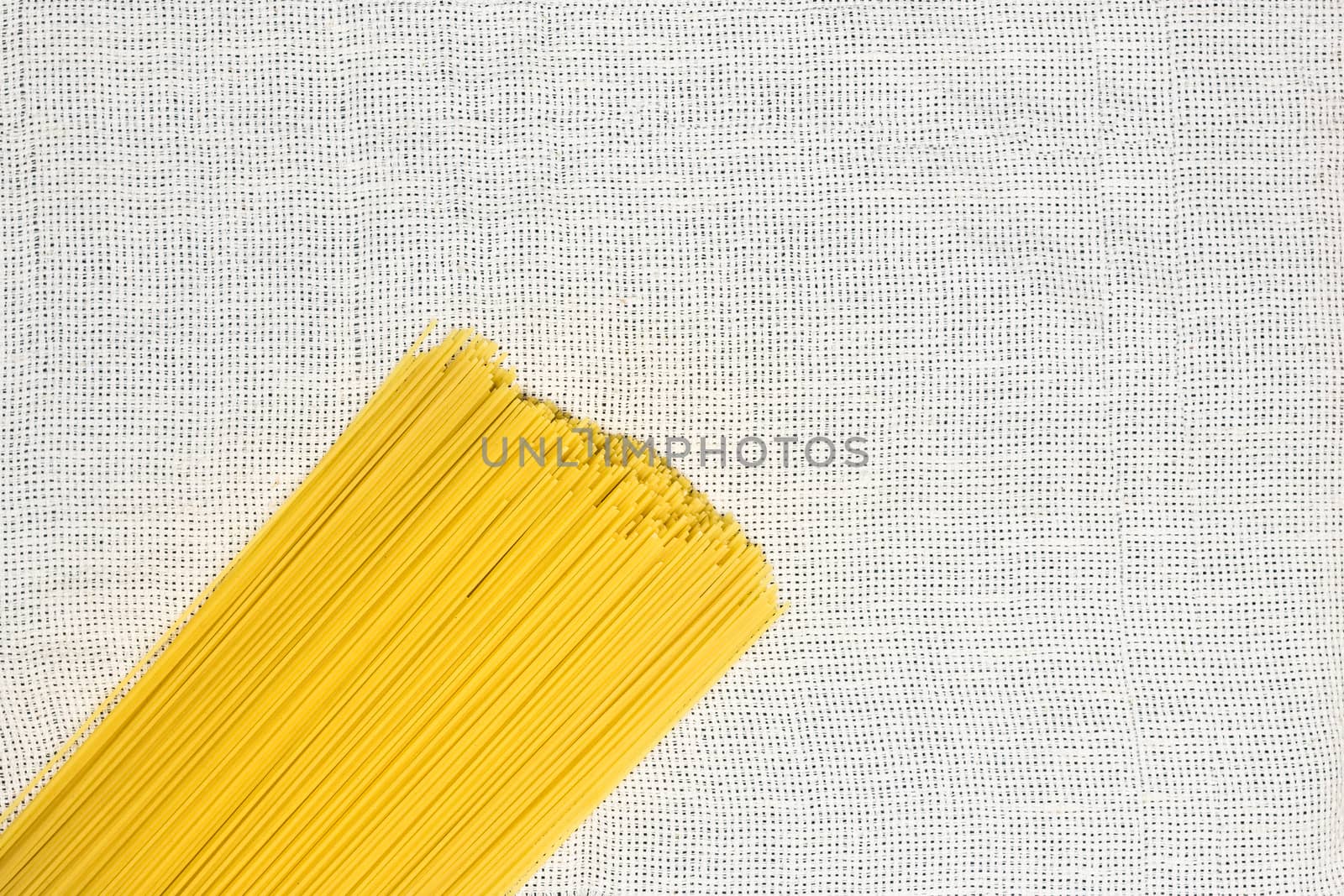 Bunch of uncooked spaghetti top view on light white canvas