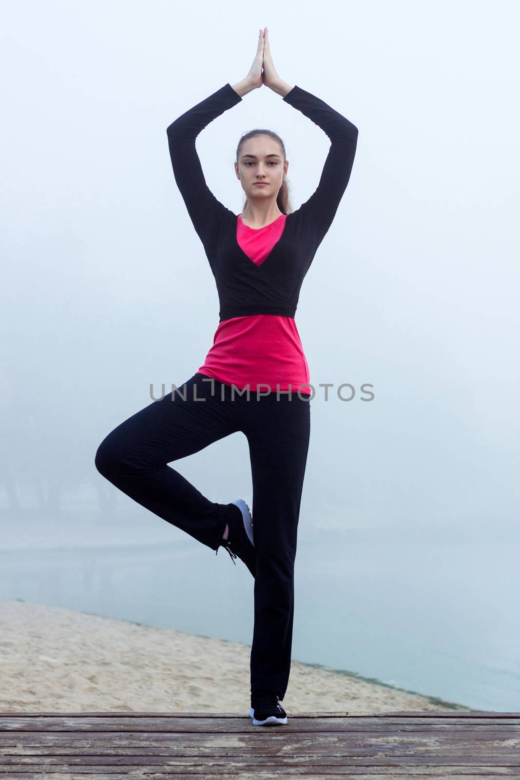 Young pretty slim fitness sporty woman does yoga exercises during training workout outdoor