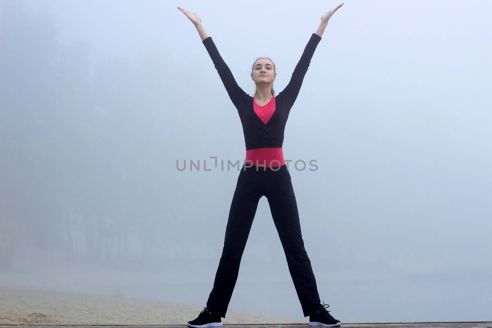 Young pretty slim fitness sporty woman does yoga exercises during training workout outdoor