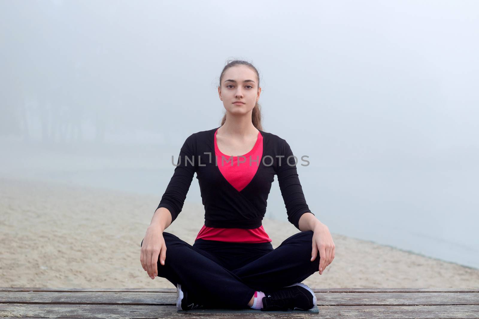 Young pretty slim fitness sporty woman does yoga exercises during training workout outdoor