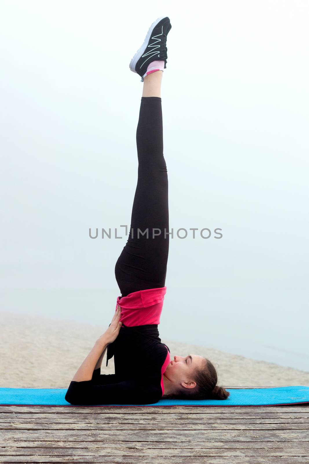 Young pretty slim fitness sporty woman does yoga exercises during training workout outdoor