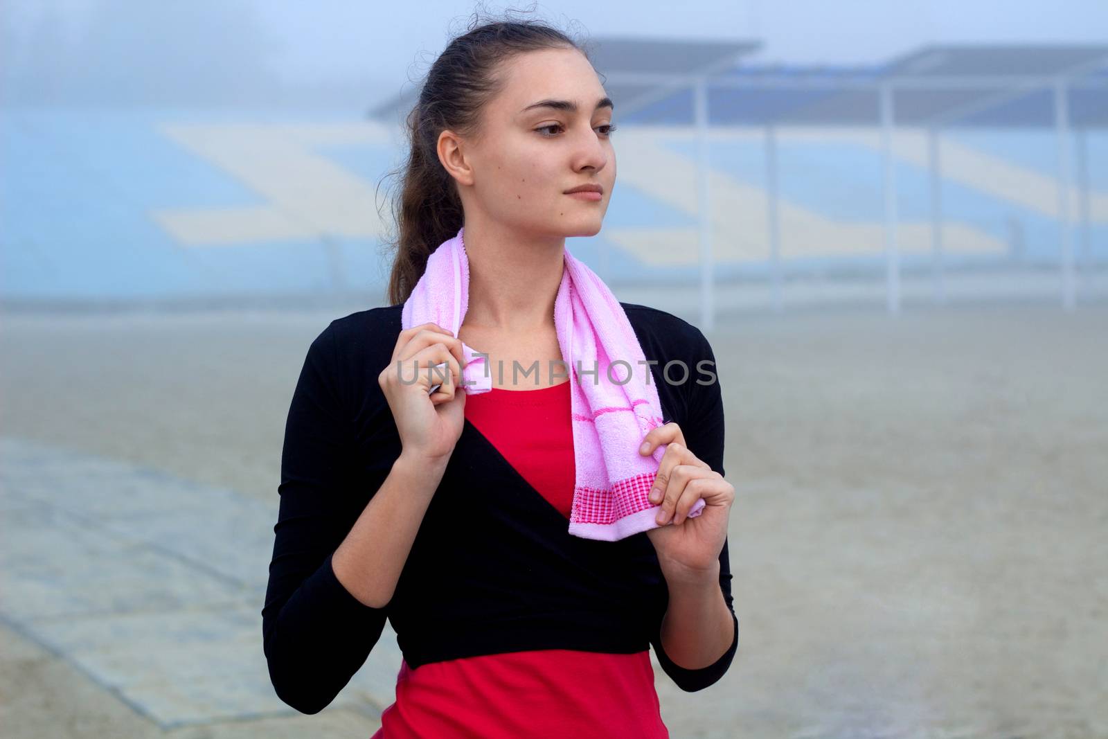 Young pretty slim fitness sporty woman with towel during break at training workout outdoor