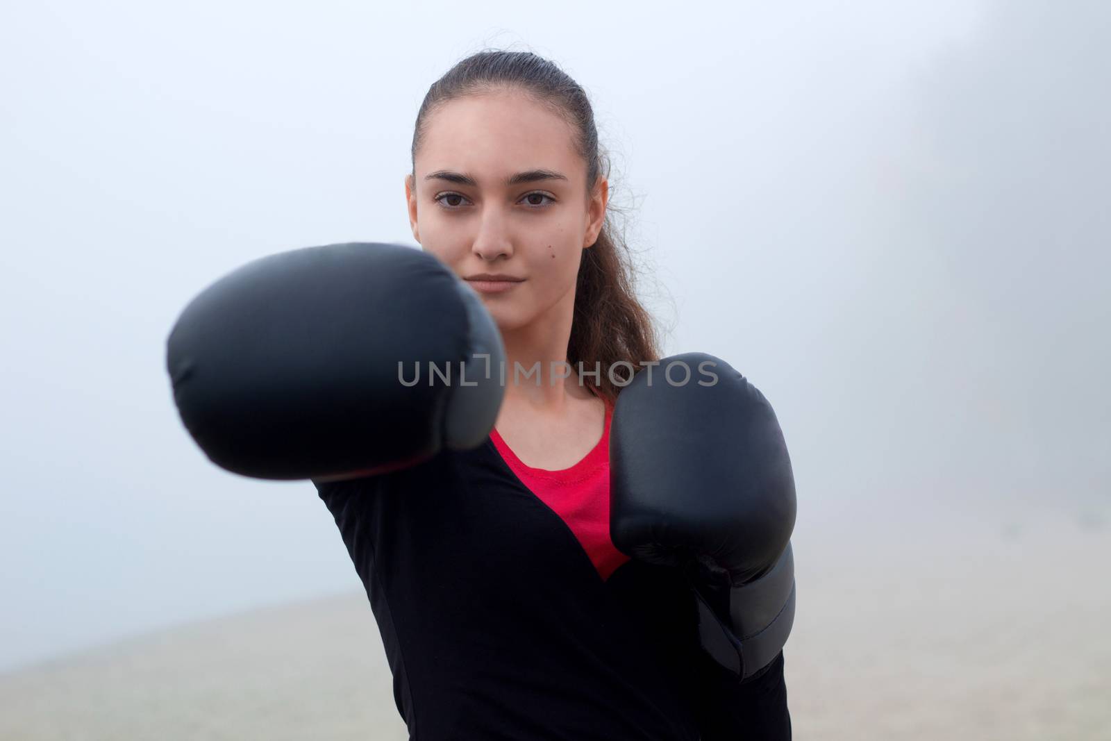 Young pretty slim fitness sporty woman does boxing exercises during training workout outdoor