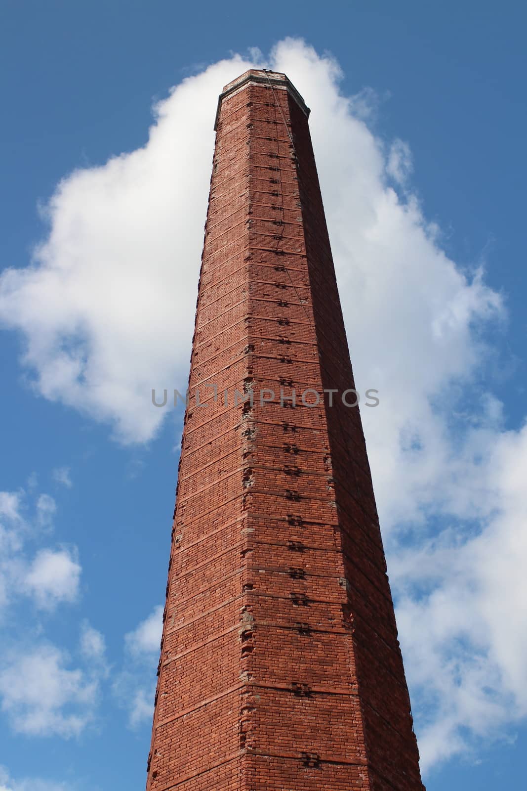 old factory chimney in red brick against the blue sky