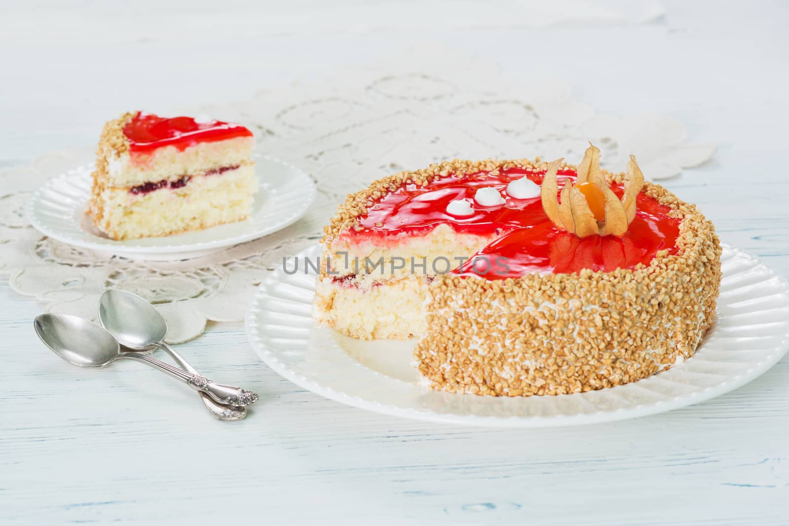 Cake with red jelly and cape gooseberry on plate on light background