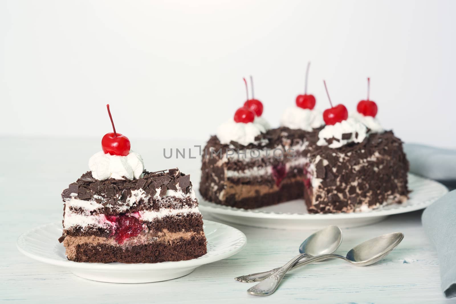 Chocolate cake with cherry on plate on light background
