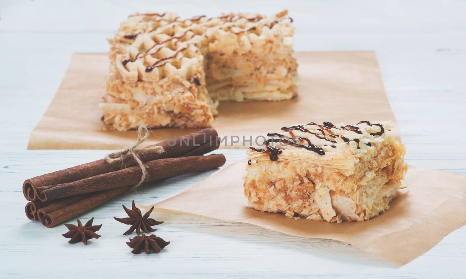 Puff cake with cinnamon sticks on baking paper on table on light background