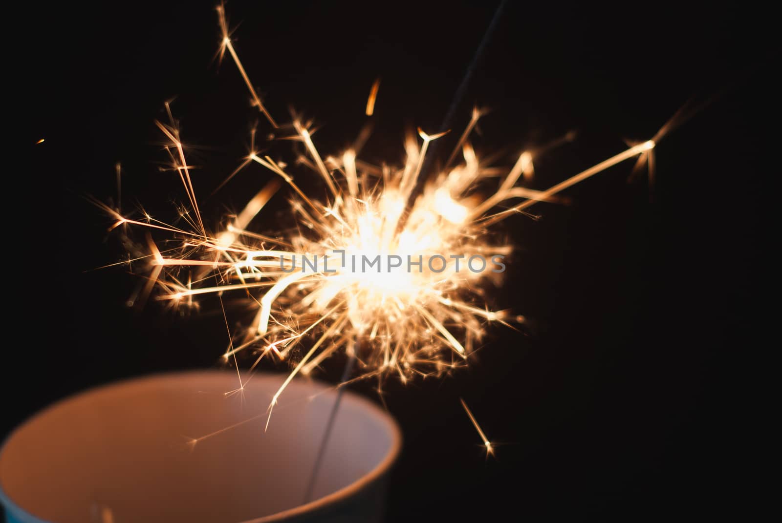 the Sparkler in a paper Cup on a black background, sparks fly in different directions, Christmas atmosphere