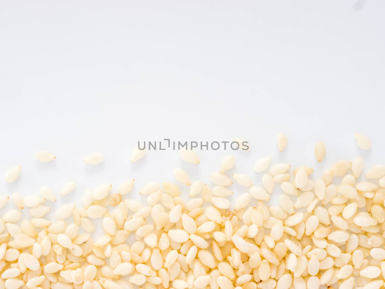 Sesame Seeds on white background with copy space. Isolated one edge. Top view or flat lay.