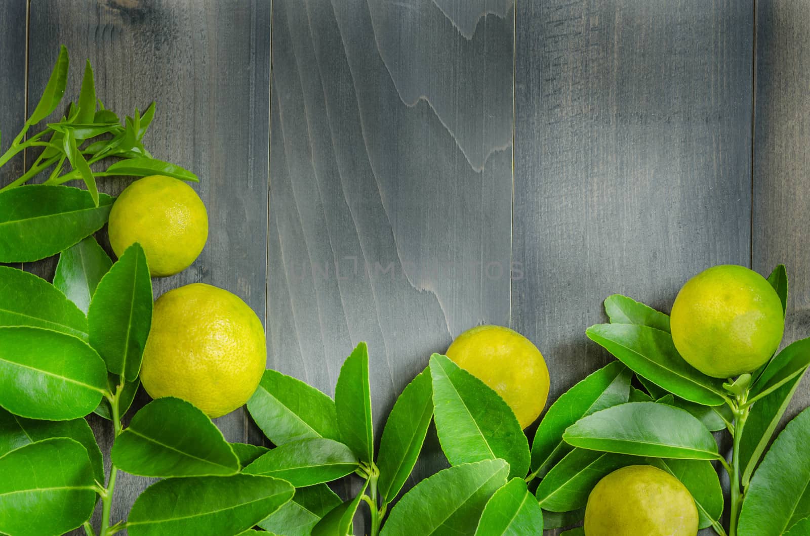 top view of wooden background with fresh lime and green leaves