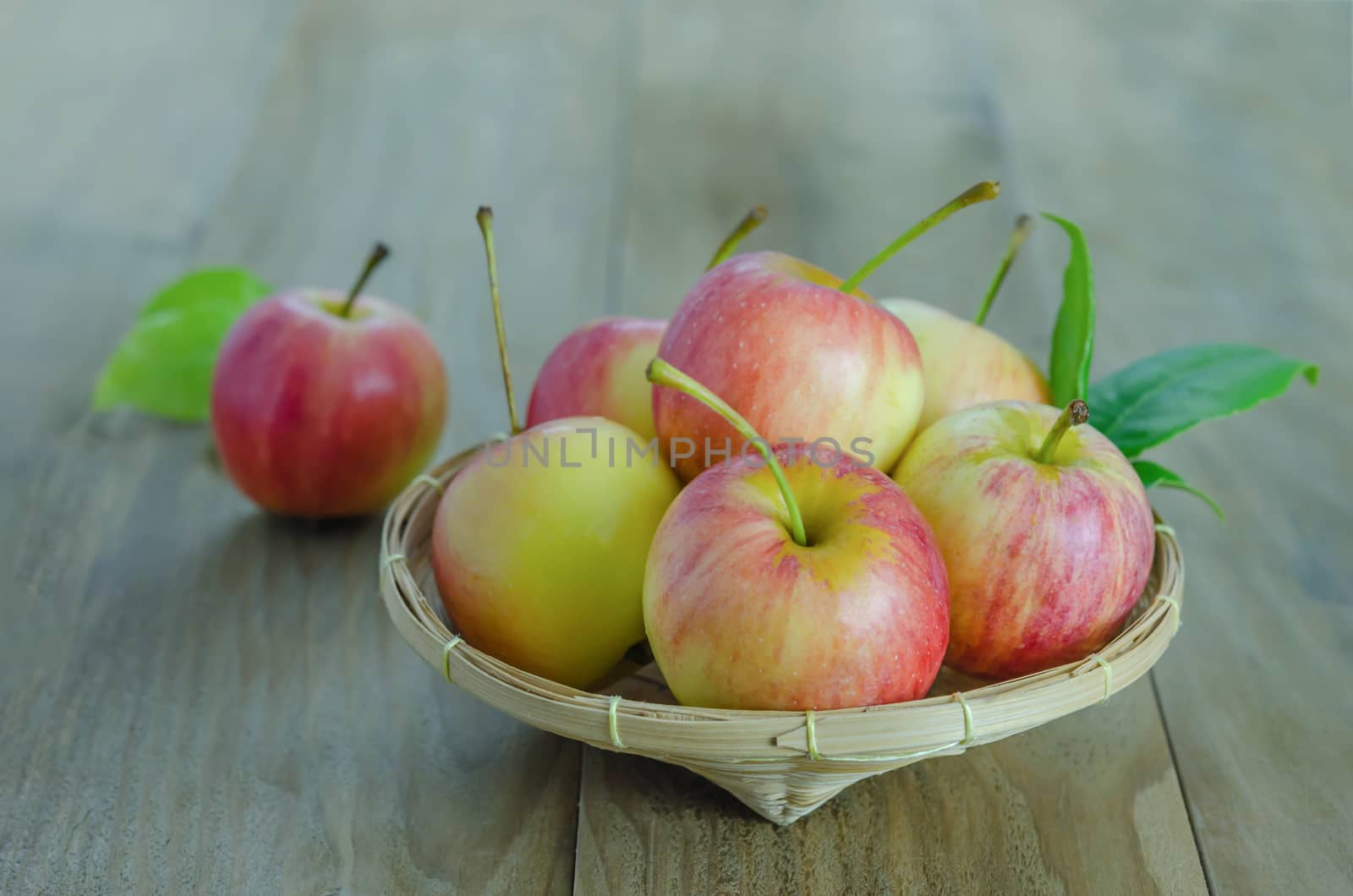 Red and yellow apple  with bamboo basket , organic fresh fruit on wooden background