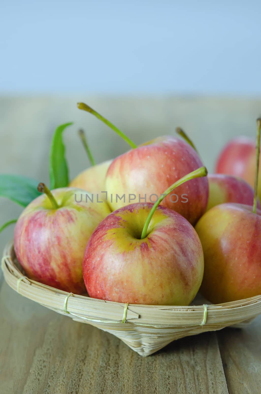 Red and yellow apple  with bamboo basket , organic fresh fruit on wooden background