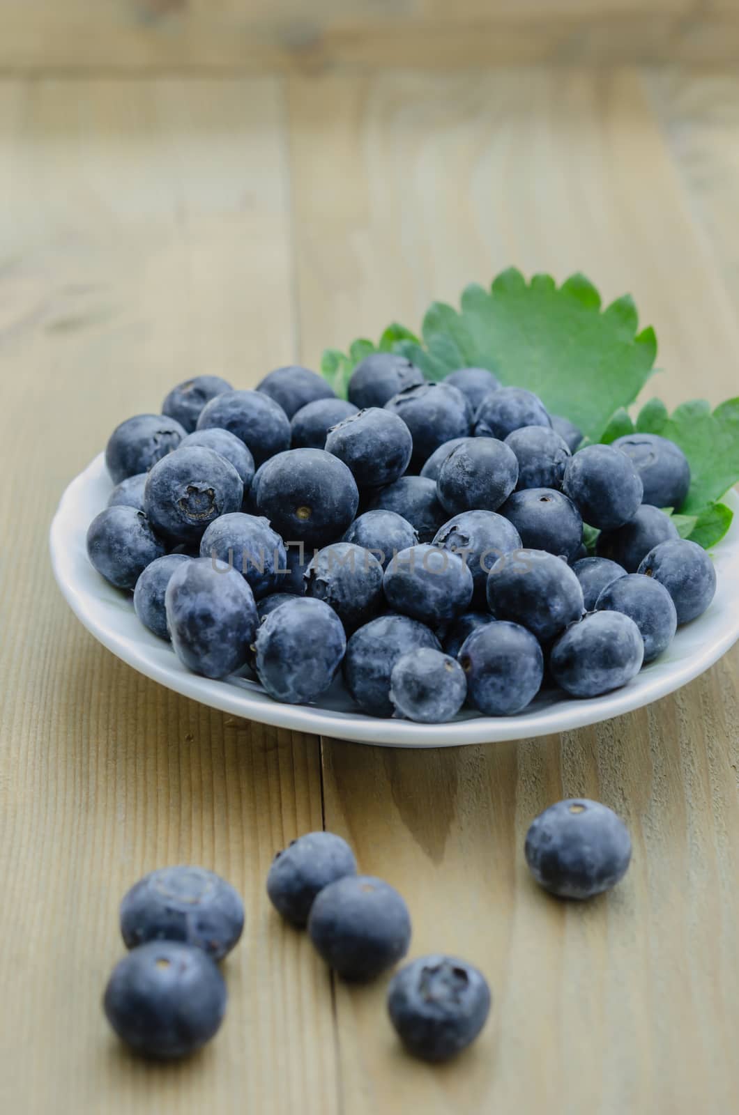Blueberries on white plate over  wooden background