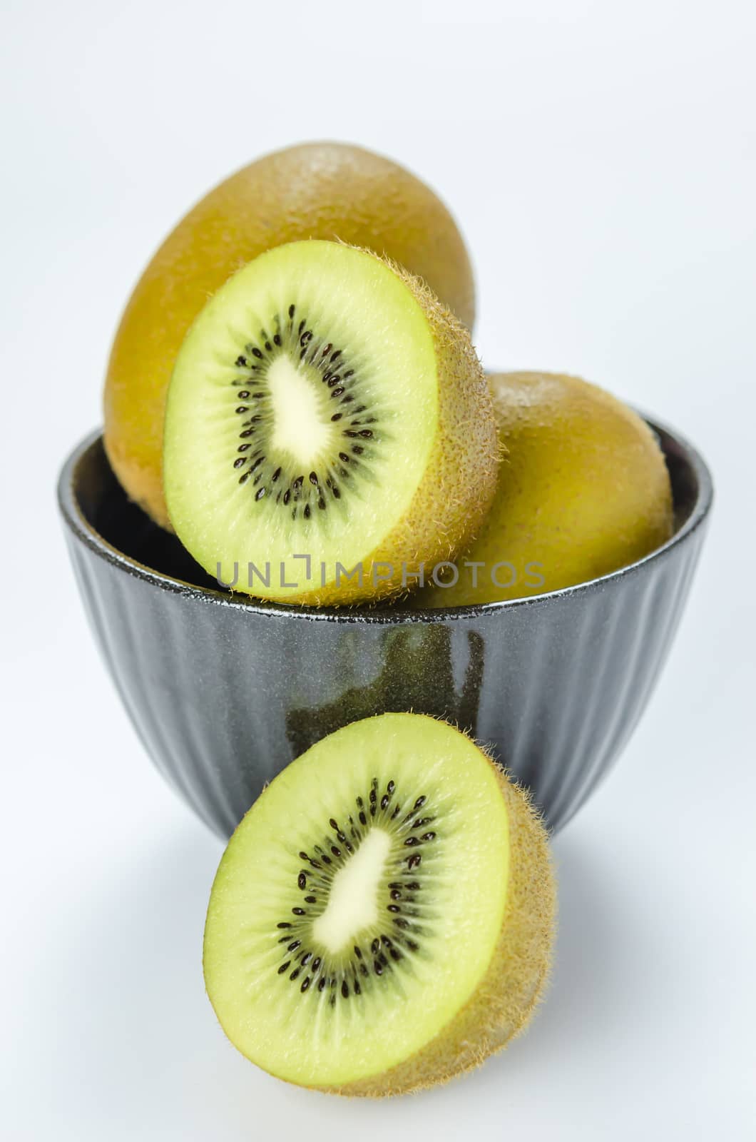 kiwi fruit and half with black bowl on white background