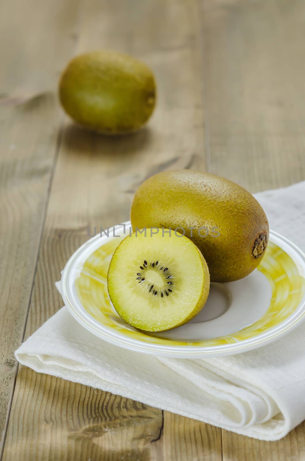 golden kiwi fruit and sliced on dish over wooden background