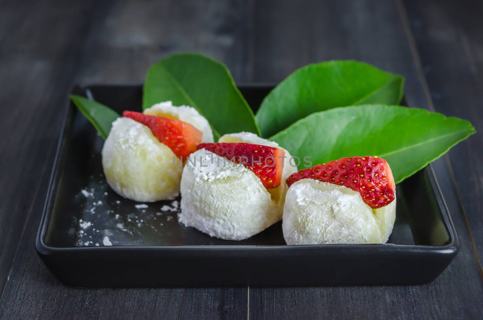 Strawberry Daifuku Mochi Japanese dessert on black dish over wooden background