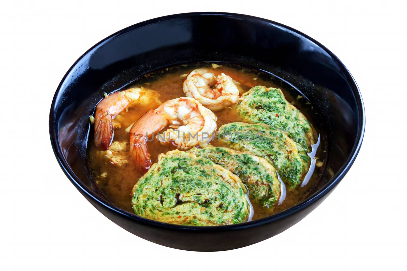 Hot and sour soup curry with shrimps and acacia pennata omelette. In black dish on white background. Objects with clipping paths.