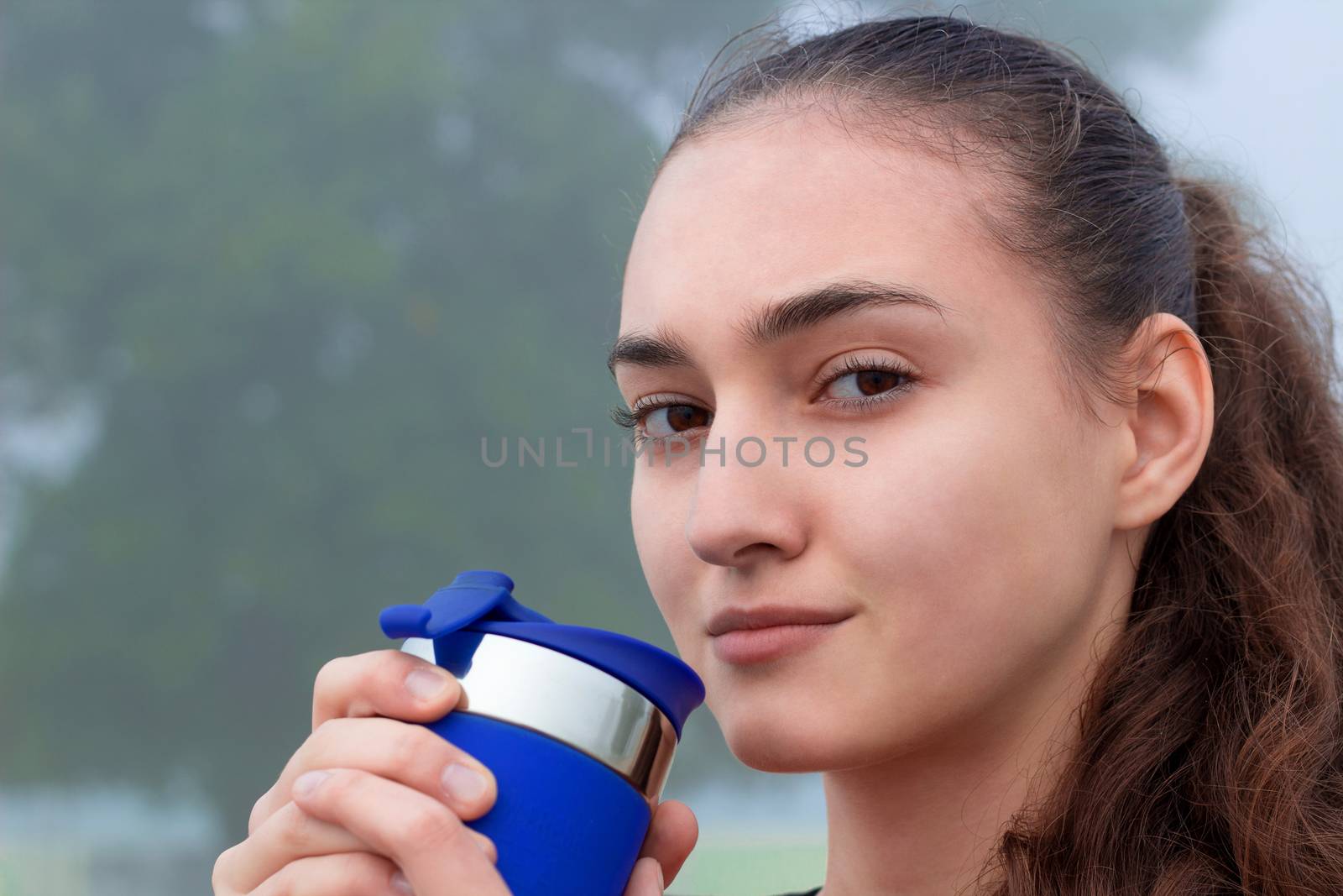 Young pretty slim fitness sporty woman drinks water during training workout outdoor