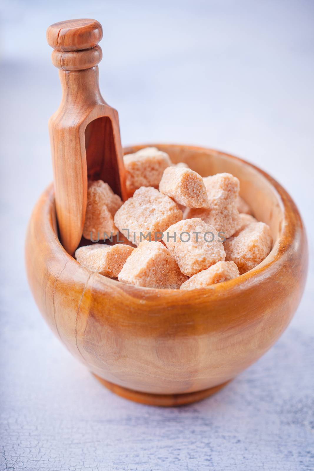 Brown cane sugar cubes in a wooden bowl.